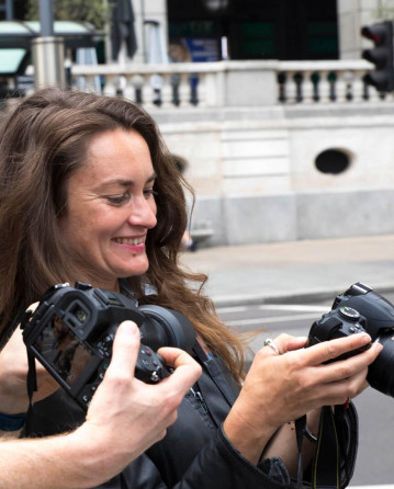 Three photographers are in Liverpool Street. One is showing the photo she has taken to the tutor.