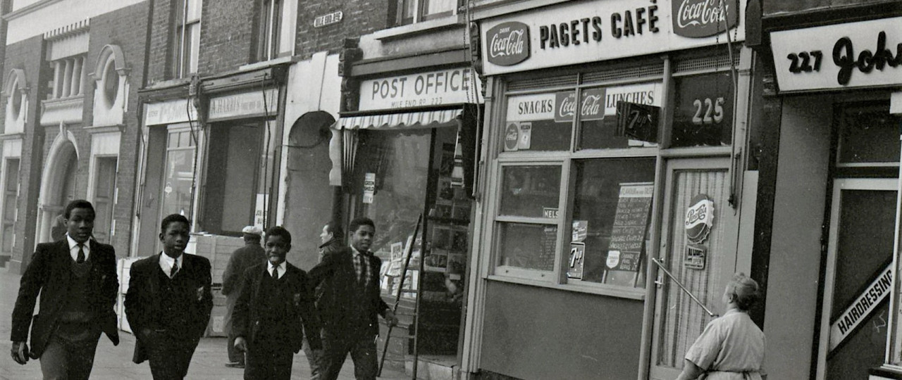 A black and white image of four young school boys walking down the street.