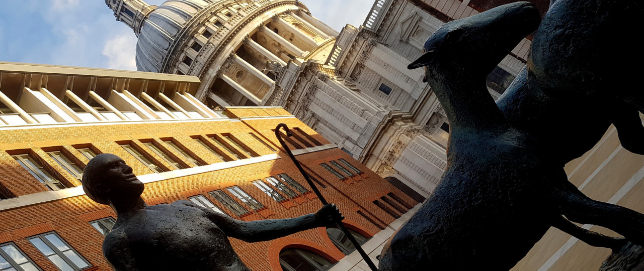 A photo taken of St. Paul's, with a statue of a men herding some sheep in front of the building.