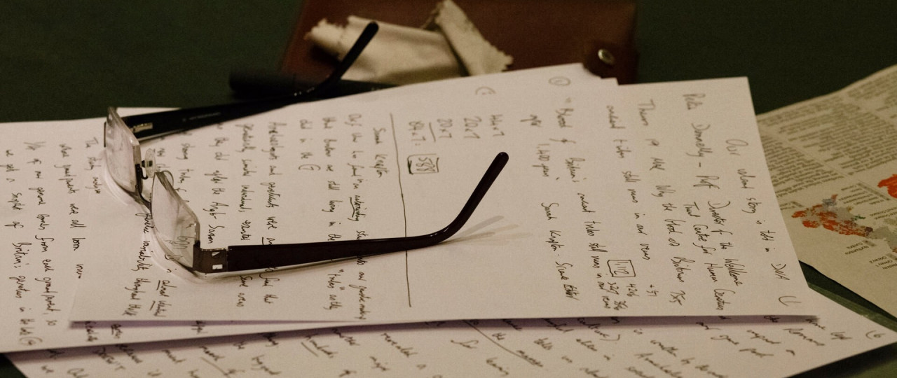 Glasses have been placed on pieces of white paper with writing on.