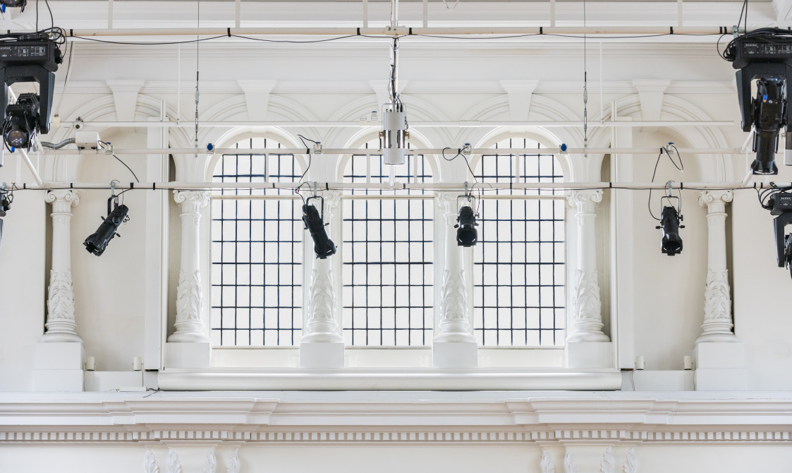 A photograph of the windows in Bishopsgate Institute's Great Hall in central London. A lighting rig is just over the windows.