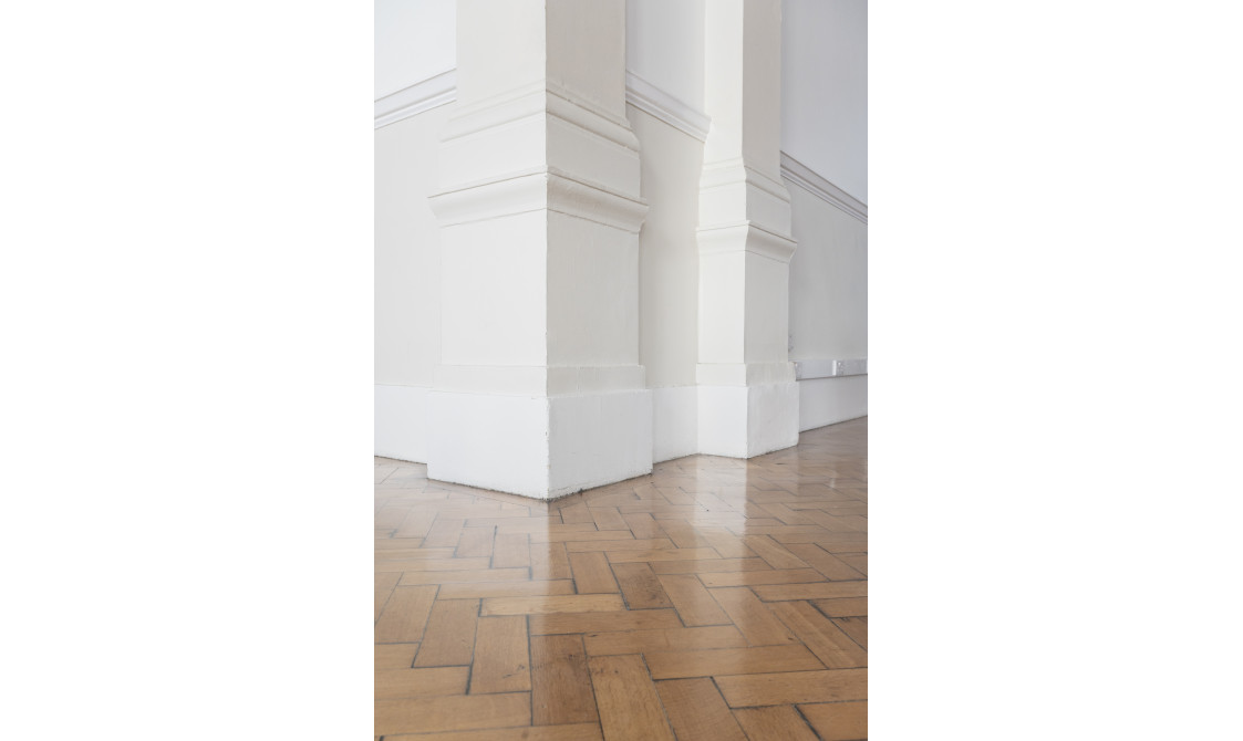 A photograph of a corner of a room at Bishopsgate Institute. The floors are laminate and the walls are white.